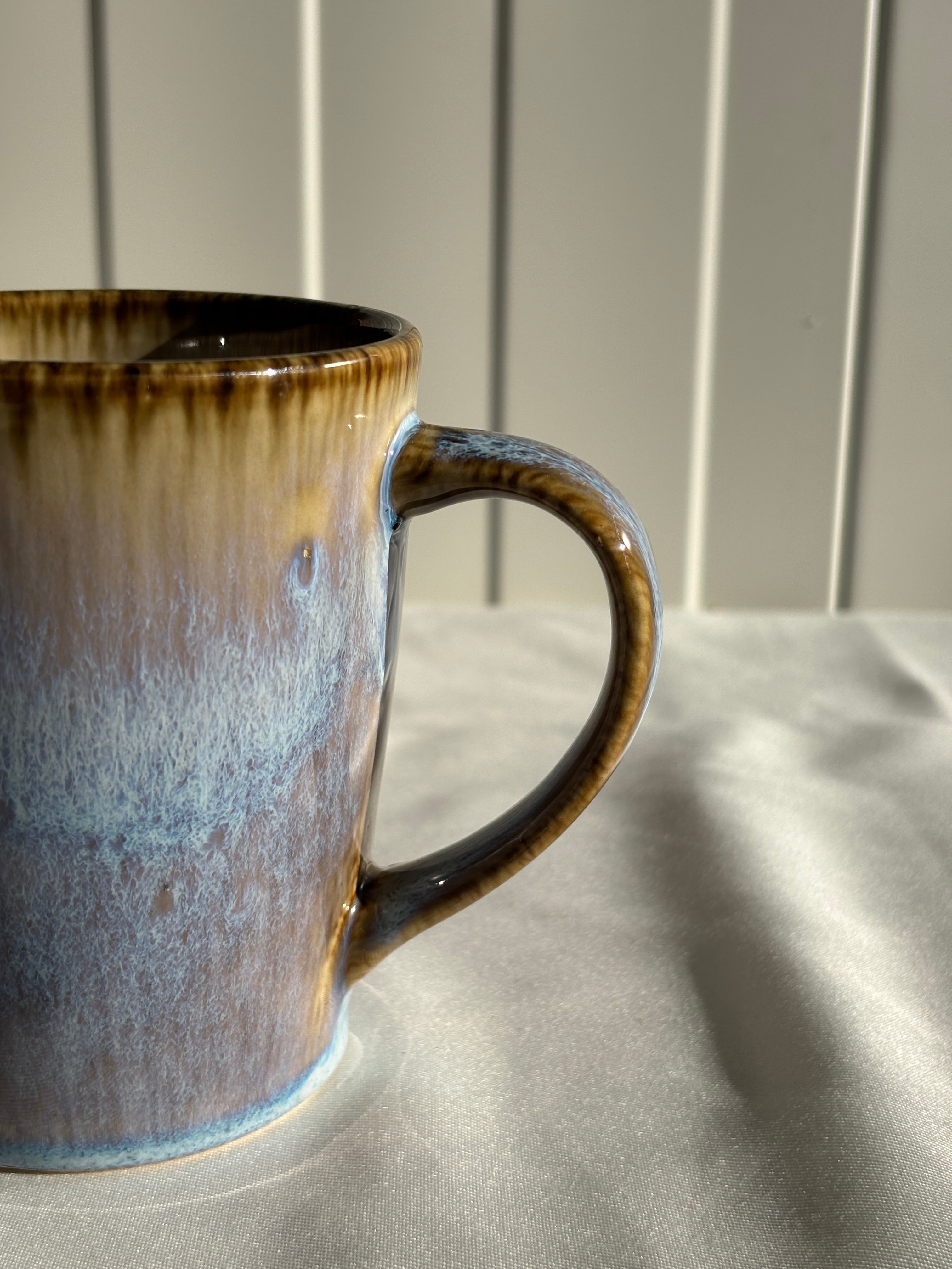 Taza de cerámica hecha a mano con esmalte reactivo azul y marrón